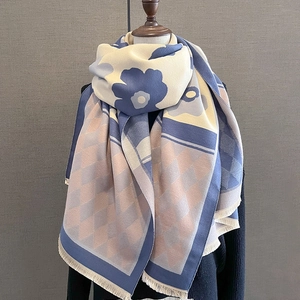 Detail of cashmere-like scarf with blue floral and diamond patterns and fringe trim