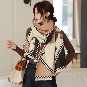 Detail view of the thick cashmere-like scarf with geometric patterns and tassels