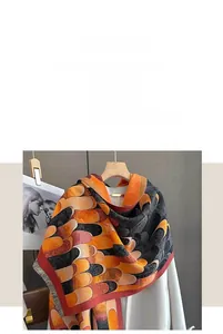 Detail of color block faux cashmere scarf featuring orange geometric patterns and fringes