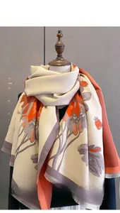 Close-up of thick winter scarf featuring red floral print and delicate fringe edges
