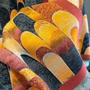 Detail of color-block knit scarf showing abstract patterns and neat fringe edges