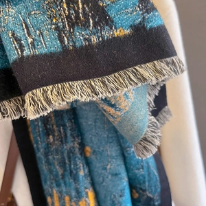 Detailed view of abstract oil painting patterns and fine tassels on a warm scarf