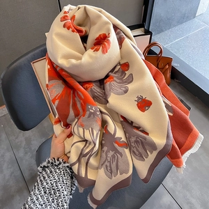 Close-up of thick floral cashmere-like scarf with orange flowers and soft fringe edge