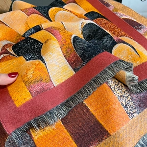 Close-up of geometric pattern jacquard shawl with decorative fringe and tassels