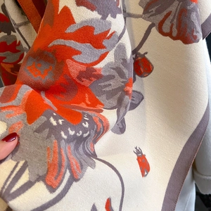 Close-up of soft cashmere-feel scarf fabric with floral print and ladybug pattern detail