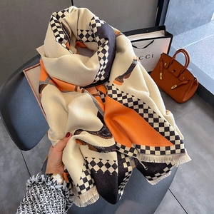 Detail of soft cashmere-like scarf featuring orange and cream patchwork with fringe
