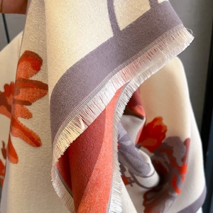 Close-up of double-sided printed cashmere-like scarf with fringe edges and floral patterns