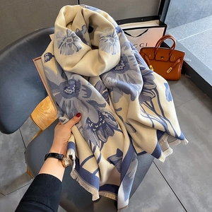Close-up of soft cashmere-like scarf with blue floral prints and tassel edge detail
