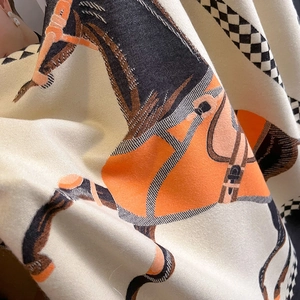 Detailed close-up of cashmere-style shawl with classic horse bridle print and soft texture