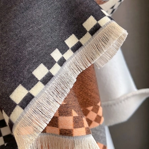 Detailed macro view of checkered cashmere-feel scarf with fine fringe edges and knit texture