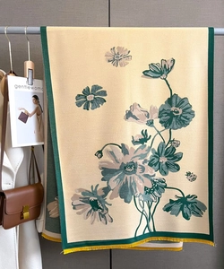 Detail of yellow double-sided cashmere scarf with floral patterns and vibrant tassels