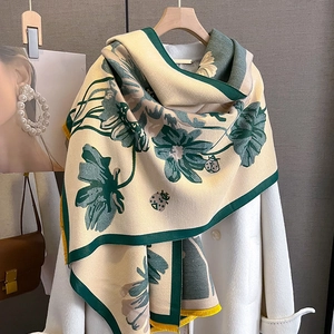 Detail of cashmere-like scarf showing green floral prints and yellow tassel edges