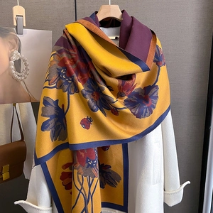 Detailed texture of thick cashmere-like scarf with warm yellow floral patterns on coat