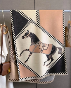 Detail of cashmere-like scarf showing horse pattern and fringe in beige and orange