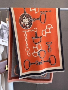 Detail of horsebit pattern and chain print on orange cashmere-feel scarf with fringes
