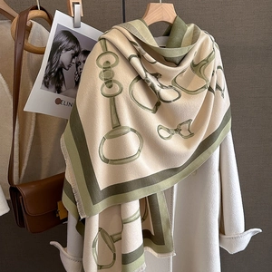 Detail of soft imitation cashmere scarf with green horsebit pattern over wool coat