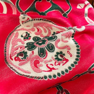 Macro detail of red thick jacquard scarf showing intricate floral weave texture