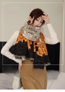 Detail of color-block imitation cashmere scarf with orange and black geometric patterns