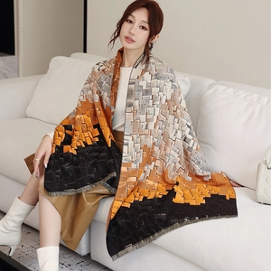 Close-up of thick knitted plaid scarf featuring orange and black geometric color blocks
