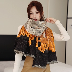 Close-up of color-block scarf with fringe edges and warm orange and black knit texture