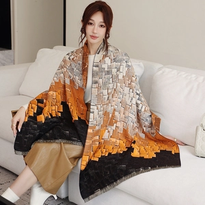Detail of soft winter shawl featuring geometric color blocks and fringe edges on a sofa