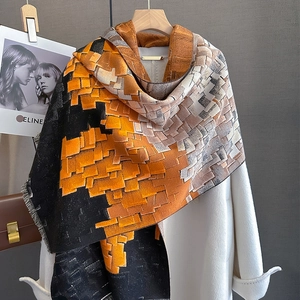 Thick oversized winter scarf with orange and black geometric blocks on a white coat
