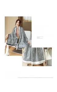 Close-up of soft cashmere-like fabric with geometric diamond patterns and delicate tassels