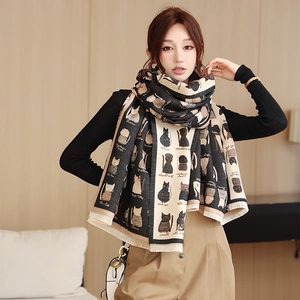 Close-up of winter scarf with black and white cat patterns and tassel edge detail