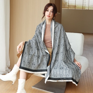 Detailed view of black and white diamond pattern scarf with fine fringe trim