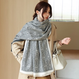 Close-up of geometric black and white scarf with tassels on khaki trench coat