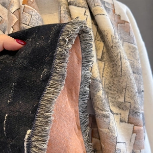 Detail of soft winter scarf showing geometric patterns, fringe edges and thick woven texture