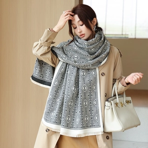 Detail view of the black and white geometric lattice pattern and soft tassel edges on the scarf