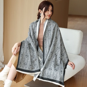 Detail of black and white geometric lattice scarf with fringe and fine knit texture
