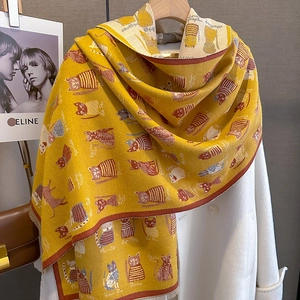 Detail of ginger cashmere knit scarf featuring colorful cartoon cat motifs and fringe edges
