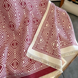 Close-up of red and white geometric diamond pattern on scarf with beige tassel fringe