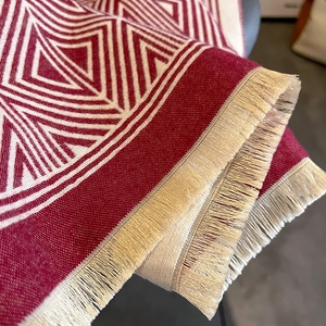 Detail of red and white geometric checkered winter scarf featuring fringe tassels
