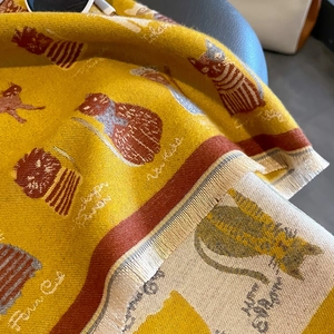 Detailed view of ginger yellow cashmere scarf featuring cat patterns and fine tassels