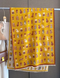 Detailed texture of yellow cashmere-like scarf with cartoon cat prints and tassels