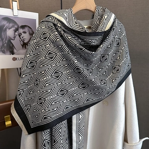Detail of black and white geometric triangle pattern scarf with fringe on white coat