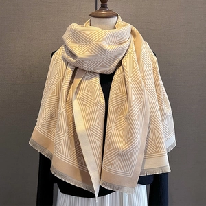 Detail of beige plaid scarf with soft tassels and warm geometric knit texture