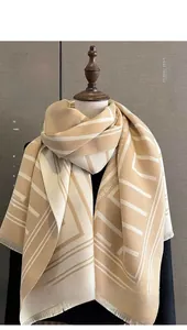 Close-up of geometric letters and fringe on beige cashmere-like knit shawl scarf