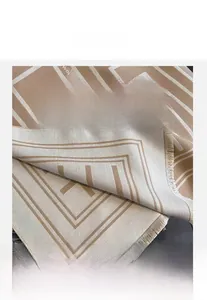 Detailed view of beige imitation cashmere scarf with geometric Greek key patterns and tassels