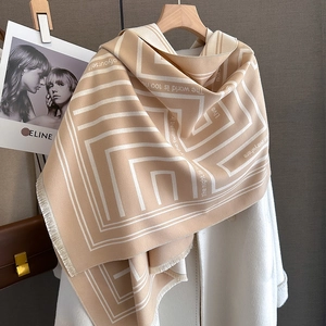 Detail of camel and white geometric scarf with quote and fringe edge on hanger