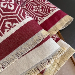 Detail eines Winterschals mit Vintage-Geometriemuster und beigen Fransen-Texturen