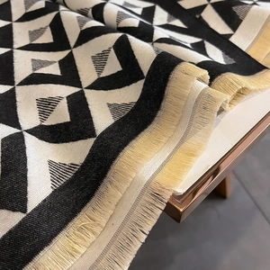 Detailed close-up of thick geometric diamond pattern scarf with long beige tassels