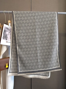 Detail eines dunkelgrauen Jacquard-Schals mit geometrischen Blumenmustern und Quasten