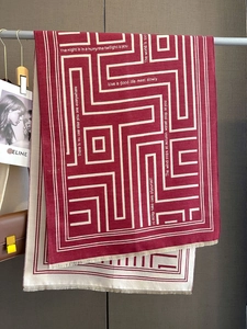 Detail view of red and beige geometric knit scarf with fringe and printed poetry text