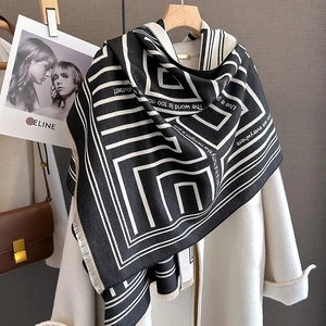 Detail of cashmere scarf with geometric lines and quote over white coat