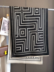 Detail of cashmere scarf with geometric maze pattern, fringe edges and stylish typography