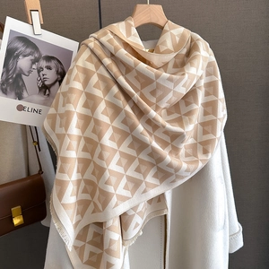 Detail of V-pattern cashmere-feel shawl with fringe edges on wooden hanger